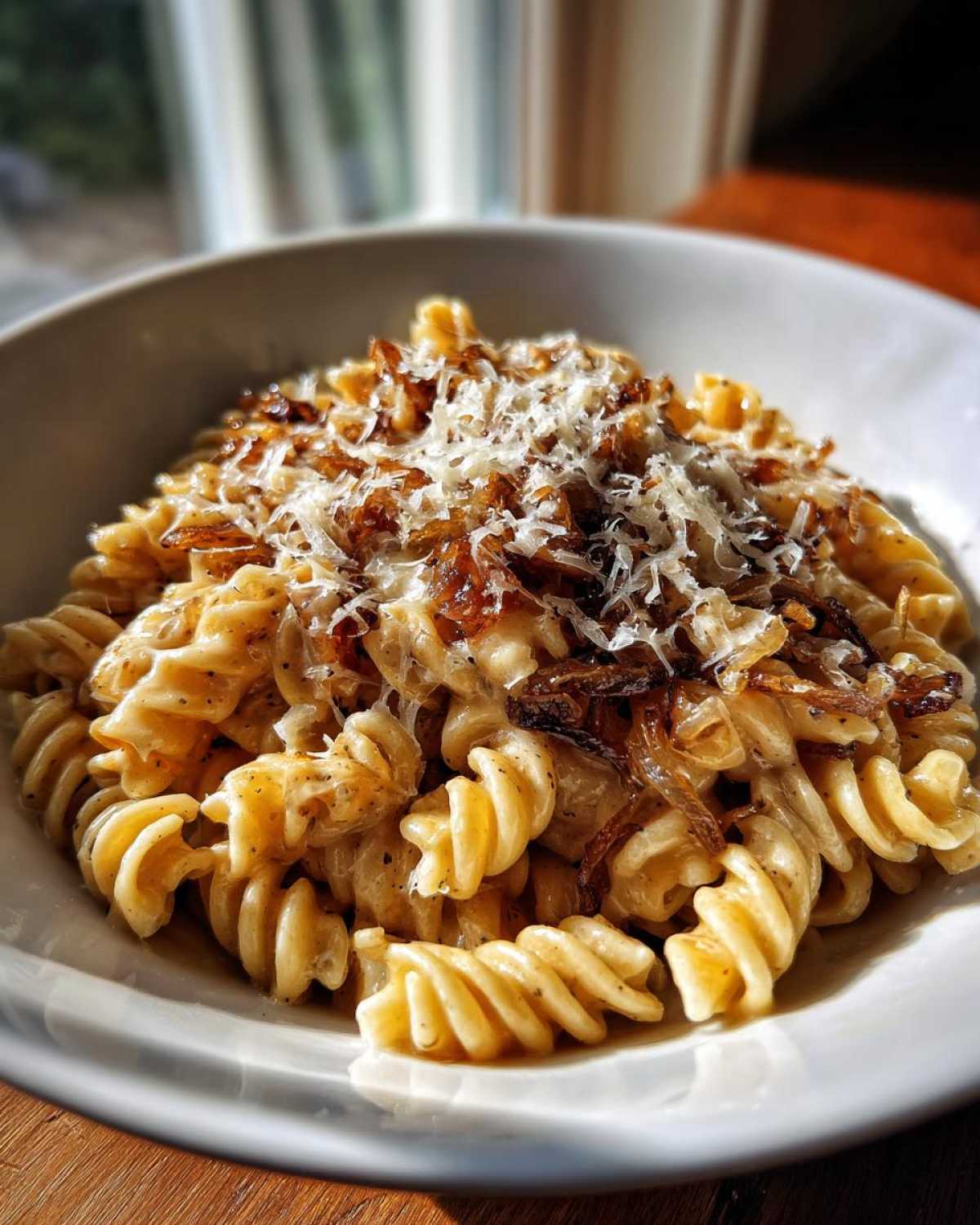 Close-up of creamy french onion pasta made with fusilli, topped with caramelized onions and grated Parmesan cheese.