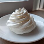 A perfectly piped swirl of white, creamy horseradish sauce served on a small white dish.