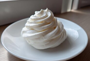 A perfectly piped swirl of white, creamy horseradish sauce served on a small white dish.
