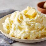 A generous serving of fluffy mashed potatoes topped with a melting pat of butter.
