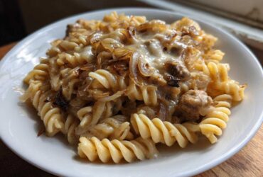 Close-up of a serving of creamy french onion pasta made with fusilli, caramelized onions, and melted cheese.