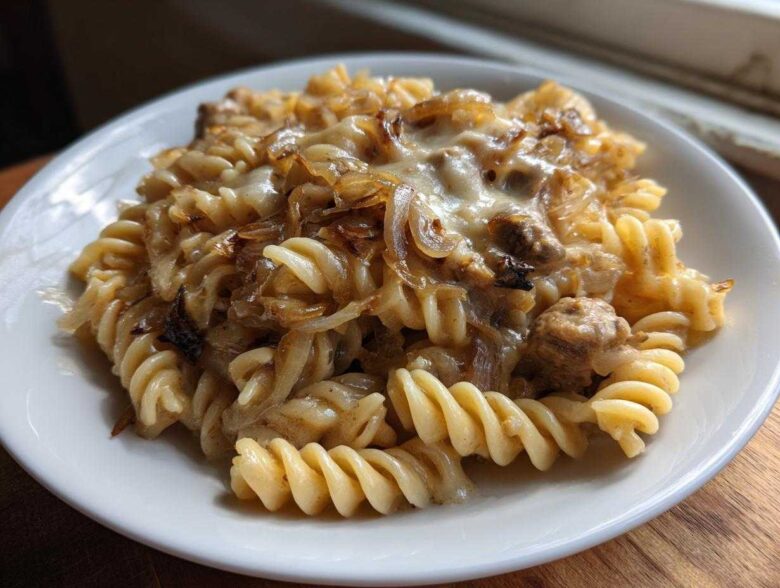 Close-up of a serving of creamy french onion pasta made with fusilli, caramelized onions, and melted cheese.
