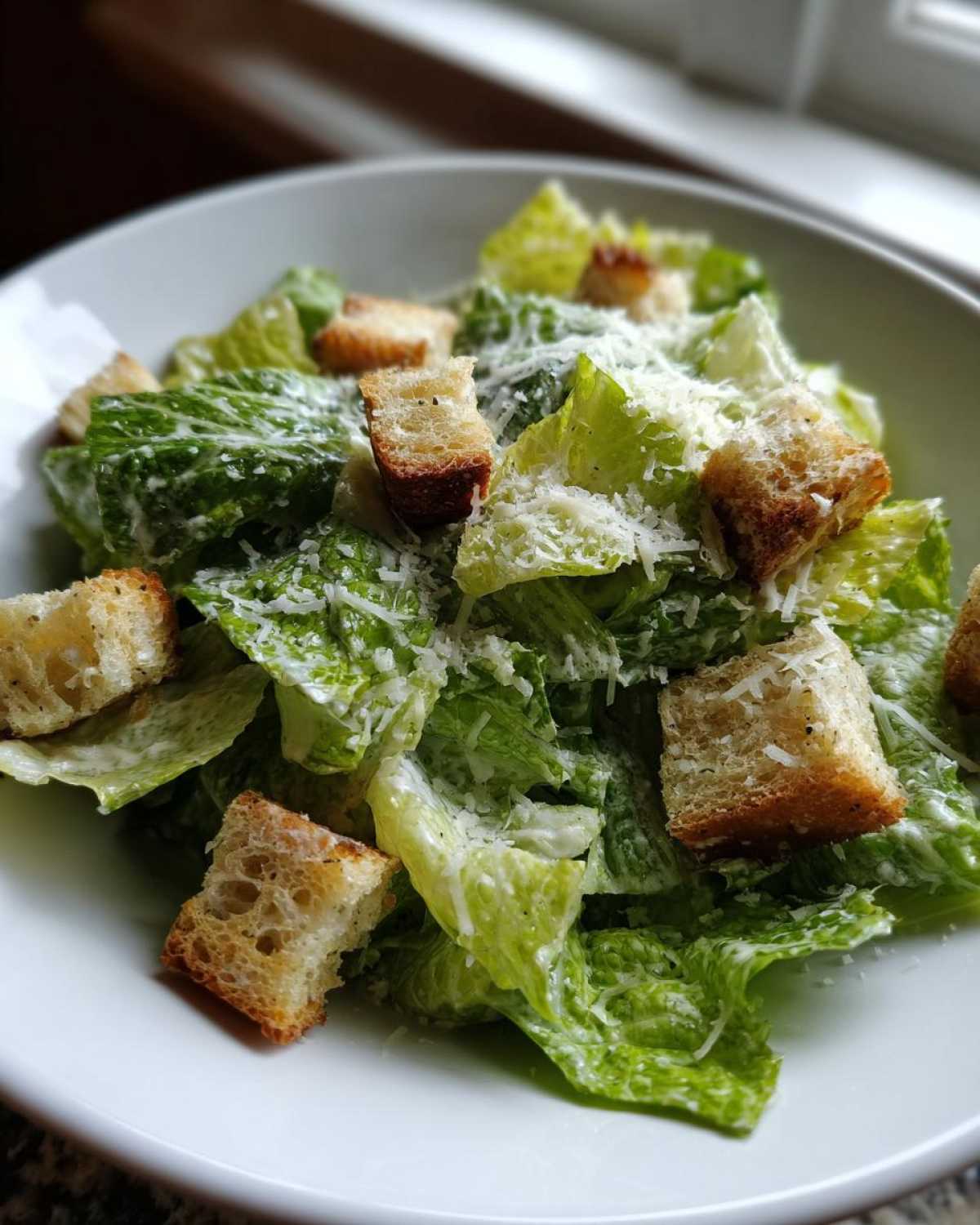 Close-up of a fresh caesar salad featuring crisp romaine lettuce, homemade croutons, and grated Parmesan cheese.