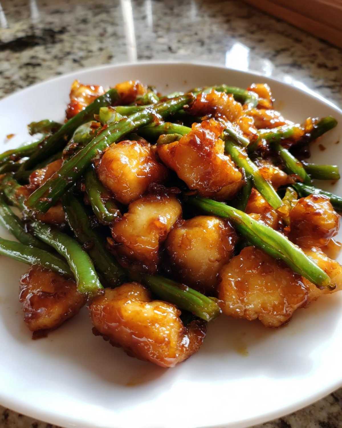 Close-up of glazed, bite-sized chicken and bright green beans, a delicious chicken and green beans dish.