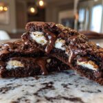 Cross-section of rich, dark hot chocolate cookies oozing melted chocolate and marshmallow filling.