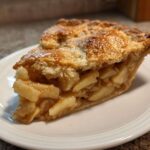 Close-up of a thick slice of homemade apple pie showing flaky crust and cinnamon-spiced apple filling.
