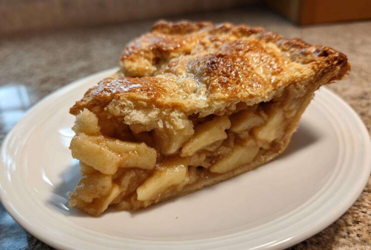 Close-up of a thick slice of homemade apple pie showing flaky crust and cinnamon-spiced apple filling.