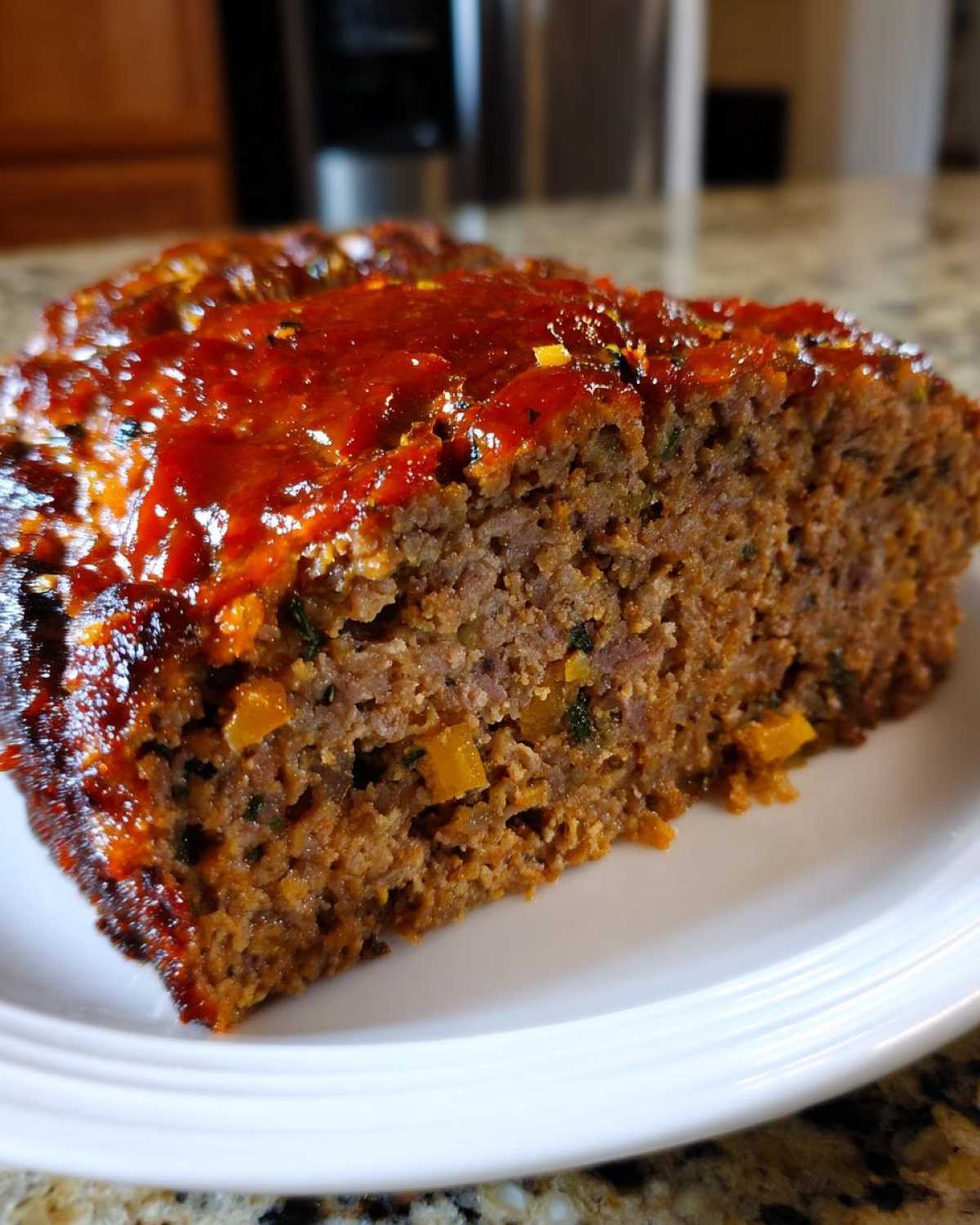 Close-up of a thick, juicy slice of meatloaf topped with a rich, red glaze.