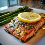 Close-up of a perfectly cooked salmon recipe fillet topped with lemon slice and herbs.