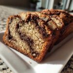Close-up of several moist slices of cinnamon swirl apple bread served on a white rectangular plate.