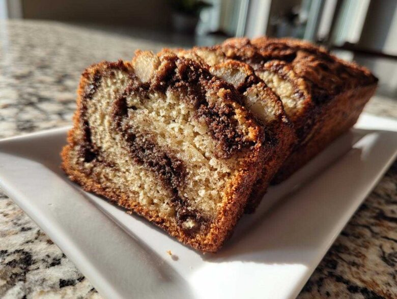 Close-up of several moist slices of cinnamon swirl apple bread served on a white rectangular plate.