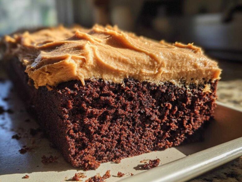 Close-up of a rich, dark brown slice of gingerbread cake topped with thick, textured peanut butter frosting.
