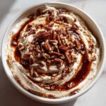 Overhead view of creamy no-bake pecan pie dip swirled with caramel and topped generously with chopped pecans.