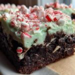 A rich, fudgy square of peppermint brownies topped with light green mint frosting and crushed candy canes.
