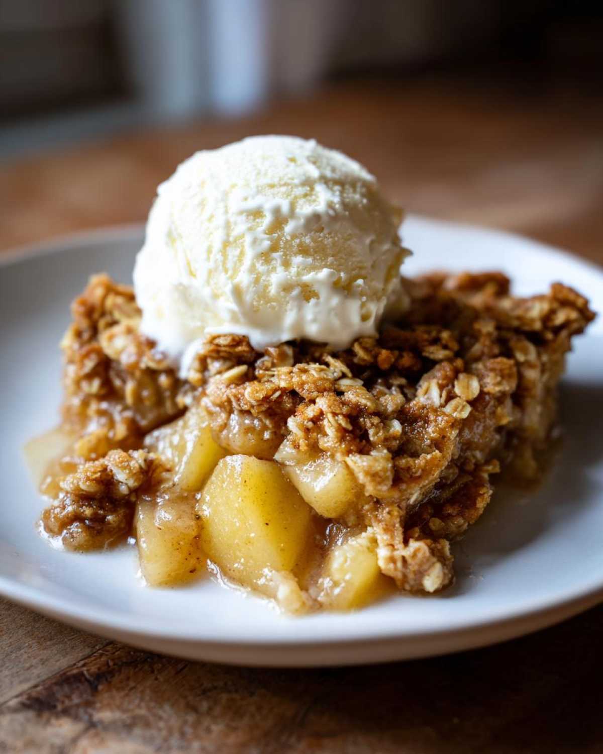 A close-up of a warm serving of pear crisp with a scoop of vanilla ice cream melting on top.