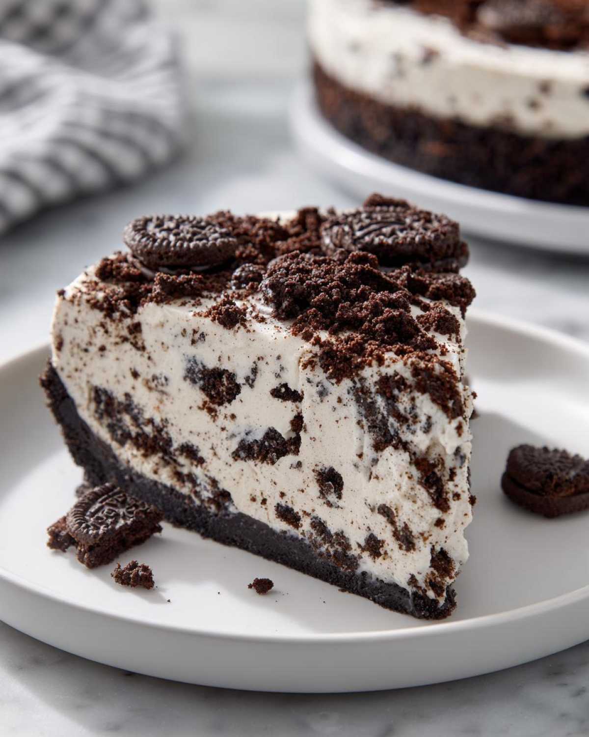 A generous slice of no-bake Oreo pie with a dark crust, creamy filling mixed with cookie pieces, and topped with crushed Oreos.