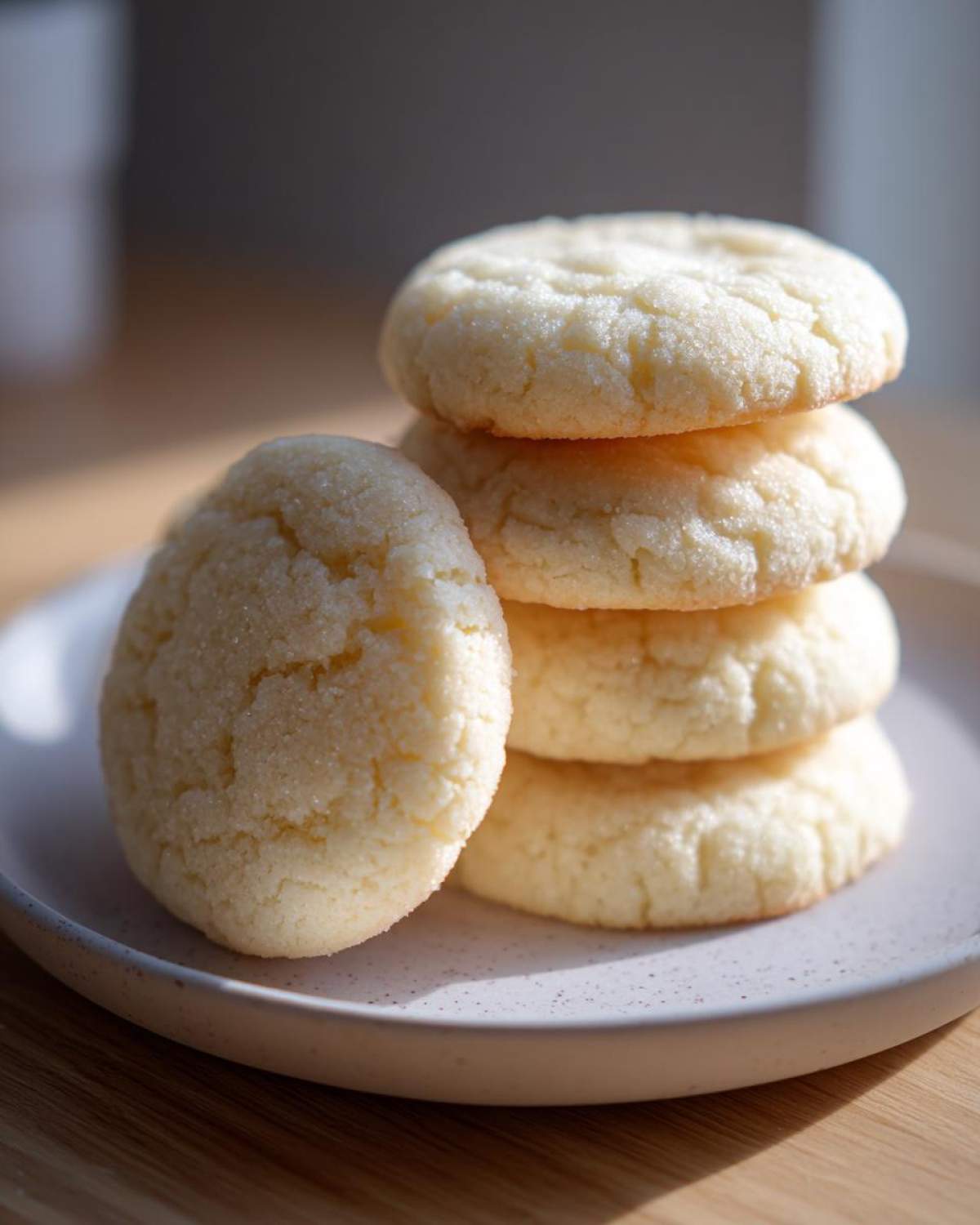 A stack of five perfectly round, light yellow soft sugar cookies dusted with sugar crystals.