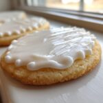 Close-up of a round sugar cookie topped with thick, glossy white sugar cookie icing recipe frosting.