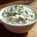 Close-up of thick, creamy 5-Minute Greek Yogurt Ranch Dip topped with fresh green dill in a white bowl.