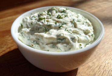 Close-up of thick, creamy 5-Minute Greek Yogurt Ranch Dip topped with fresh green dill in a white bowl.