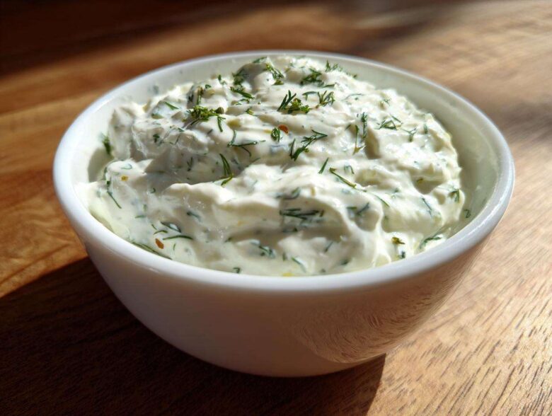 Close-up of thick, creamy 5-Minute Greek Yogurt Ranch Dip topped with fresh green dill in a white bowl.