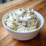 A close-up shot of thick, creamy 5-Minute Greek Yogurt Ranch Dip topped generously with fresh dill and herbs in a white bowl.