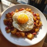 A plate of crispy Air Fryer Corned Beef Hash topped with a perfectly cooked sunny-side-up egg seasoned with pepper.