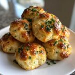 A stack of golden brown, fluffy Air Fryer Garlic Knots brushed with butter and topped with fresh parsley.
