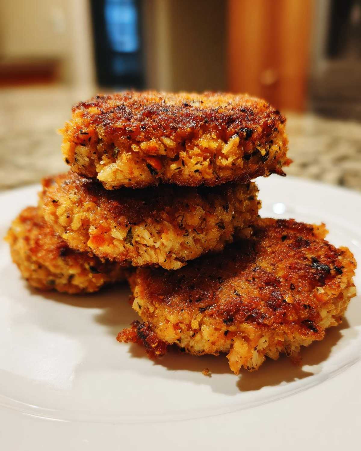 A stack of three golden-brown, crispy Air Fryer Salmon Patties resting on a white plate.