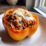 A close-up of a single, cooked yellow Air Fryer Stuffed Bell Peppers topped with melted, bubbly cheese.