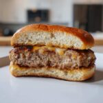 Close-up of a juicy Air Fryer Turkey Burger cut in half, showing the cooked interior and melted cheese on a brioche bun.