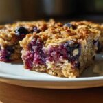 Two moist slices of Blueberry Baked Oatmeal Squares showing a rich layer of baked blueberries and an oat crumble topping.
