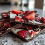 Close-up of stacked pieces of Chocolate Covered Strawberry Bark featuring dark chocolate, white drizzle, and fresh strawberry slices.