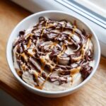A close-up of the Chocolate Peanut Butter Cheesecake Dip topped with chocolate and caramel swirls.