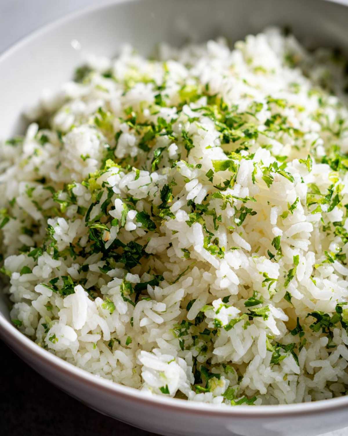 Close-up of fluffy white rice seasoned generously with chopped cilantro and lime zest, perfect Cilantro Lime Rice for Burrito Bowls.