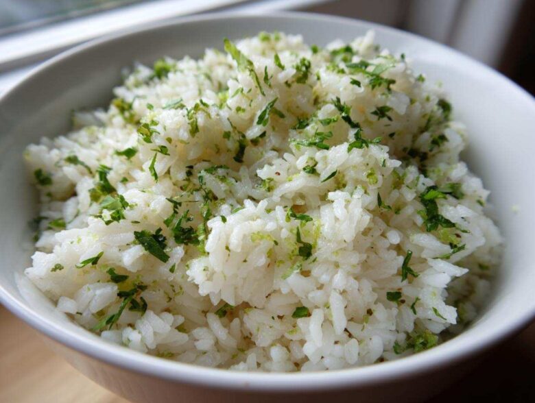 Close-up of fluffy white rice seasoned with bright green cilantro and lime zest, served in a white bowl.