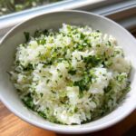 A close-up of fluffy white rice mixed with chopped cilantro and lime zest, perfect Cilantro Lime Rice for Burrito Bowls.