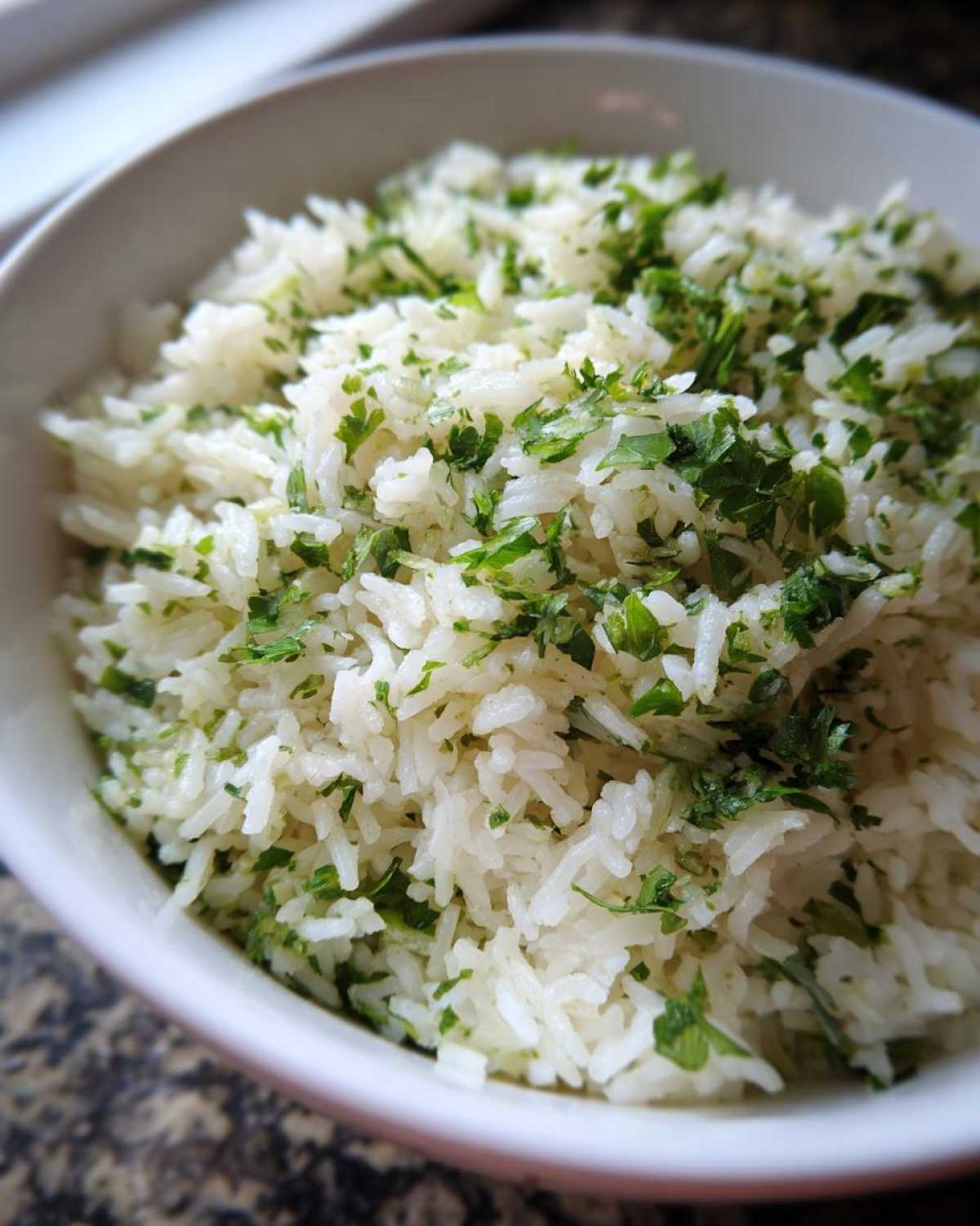 Close-up of fluffy white rice mixed with bright green chopped cilantro, perfect Cilantro Lime Rice for Burrito Bowls.