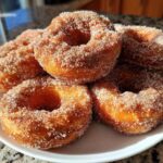 A stack of golden brown Cinnamon Sugar Air Fryer Donuts heavily coated in sparkling cinnamon sugar mixture.