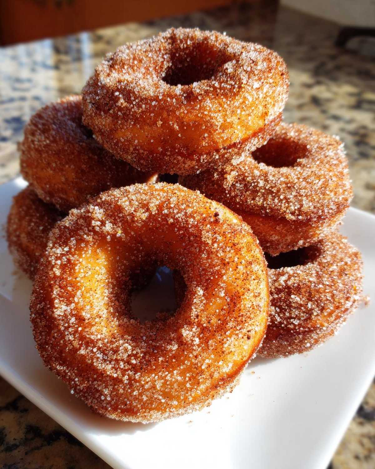 A close-up stack of golden brown Cinnamon Sugar Air Fryer Donuts generously coated in sparkling sugar.