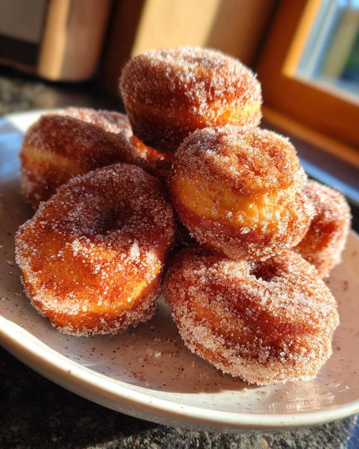 A stack of freshly made Cinnamon Sugar Air Fryer Donuts heavily coated in sparkling sugar.