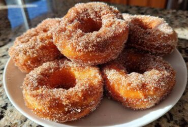 A stack of golden brown Cinnamon Sugar Air Fryer Donuts heavily coated in sparkling cinnamon sugar mixture.