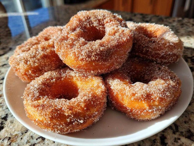 A stack of golden brown Cinnamon Sugar Air Fryer Donuts heavily coated in sparkling cinnamon sugar mixture.