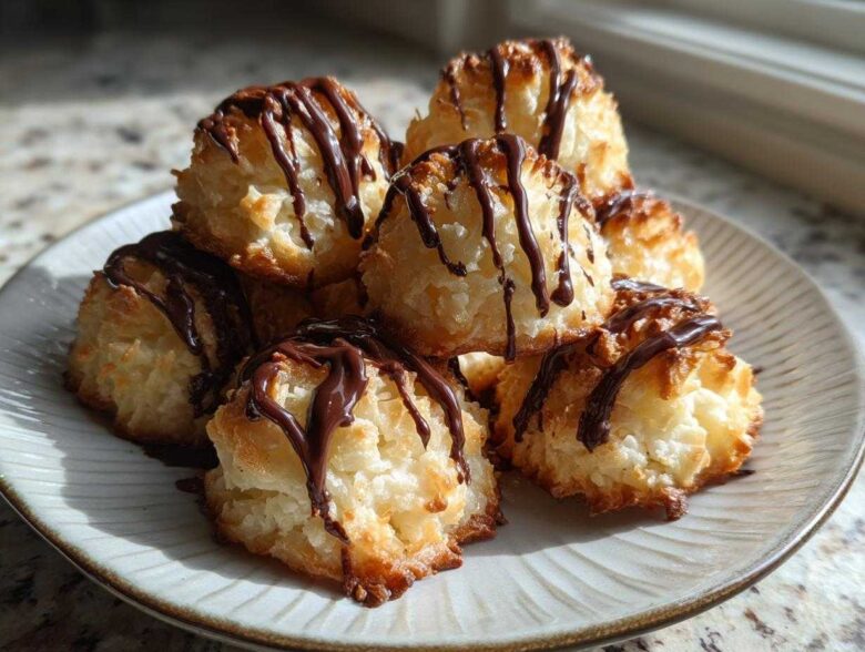 A stack of golden Coconut Macaroons with Dark Chocolate Drizzle on a light ceramic plate.