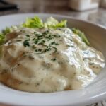 Close-up of thick, creamy Copycat Olive Garden Salad Dressing generously poured over crisp lettuce leaves in a white bowl.