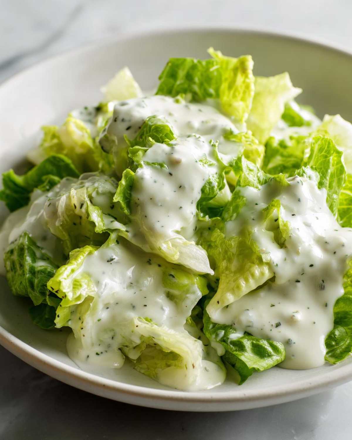 Close-up of crisp romaine lettuce generously covered in creamy Copycat Olive Garden Salad Dressing.