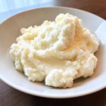 A close-up of fluffy, white Creamy Garlic Mashed Cauliflower served in a white bowl.