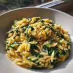 Close-up of a bowl filled with Creamy Garlic Parmesan Orzo with Spinach, topped with herbs.