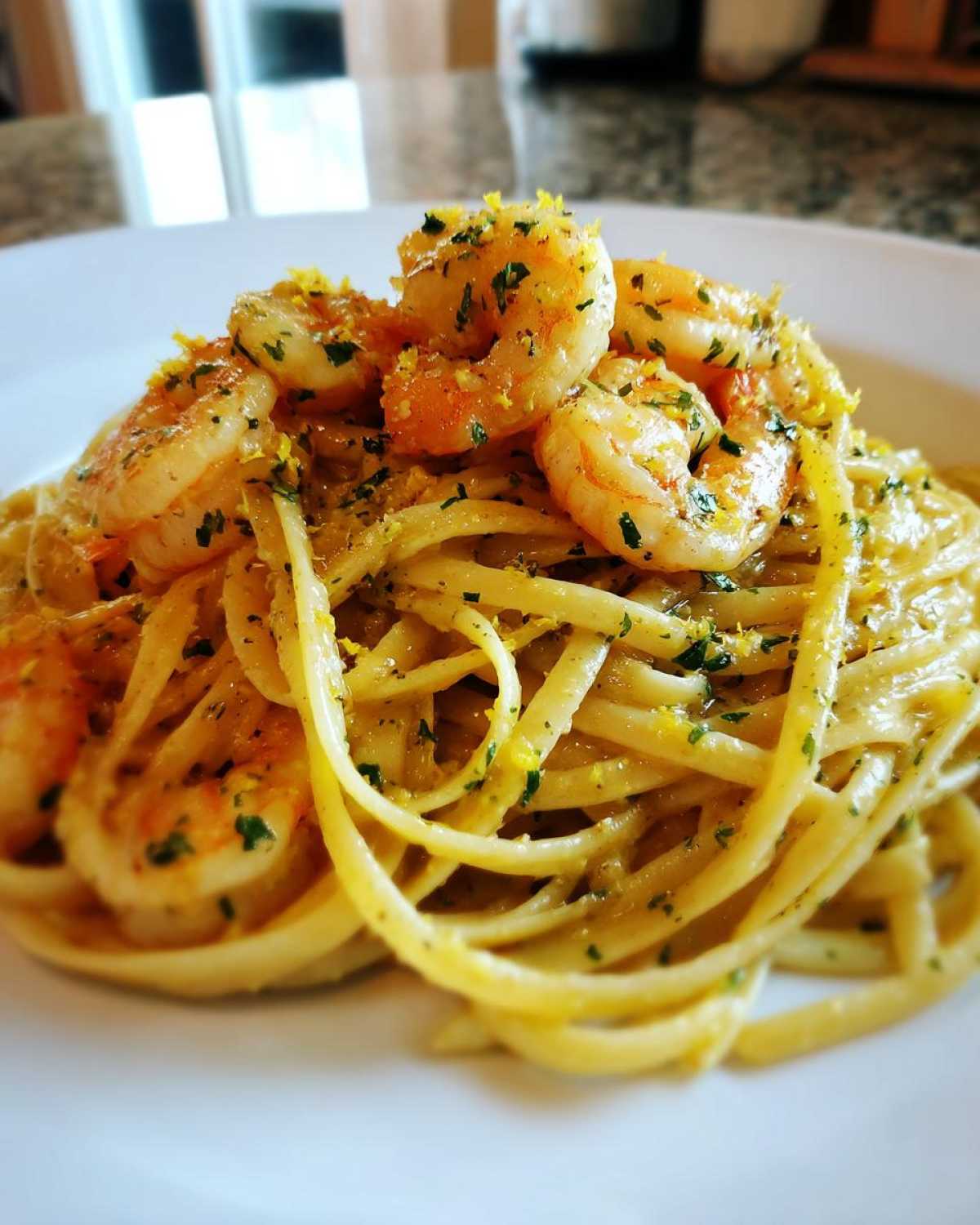 A close-up of creamy lemon garlic shrimp pasta topped with bright shrimp and lemon zest.