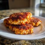 Close-up of three golden-brown, crispy Air Fryer Salmon Patties stacked on a white plate.